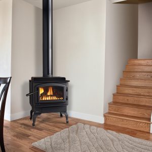 Black stove in the corner of a room simple room with a set of stairs and a some furniture