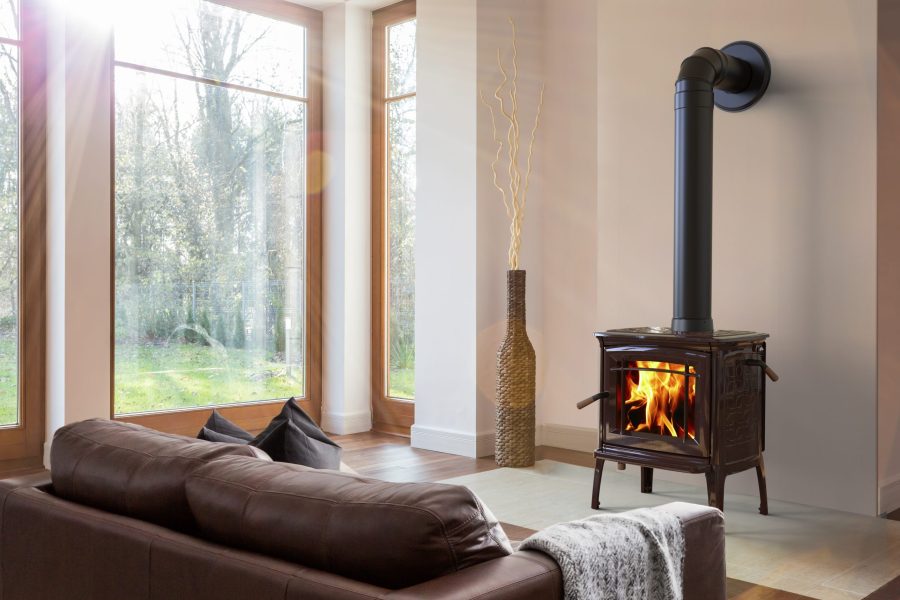 Small wood stove in a small room with large windows and a couch