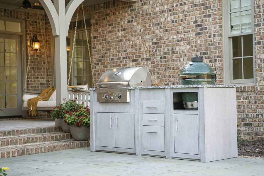 Outdoor kitchen built next to the entrance to a brick house with an arch support infront of the door