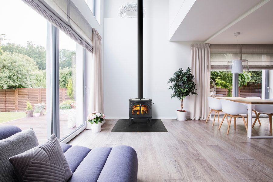 Black woodstove in a modern living room with large windows