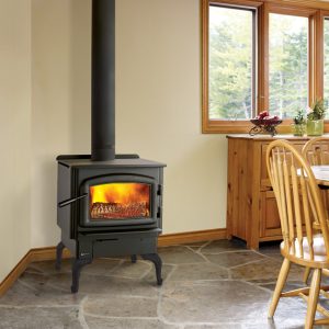 Woodstove in a dining room with wood trim and a window outlooking some woods