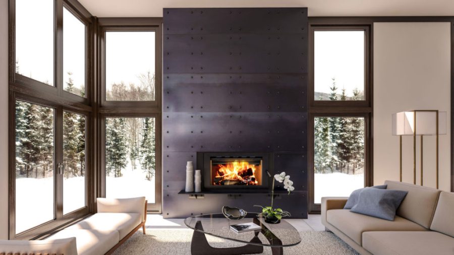 Wood fireplace insert built into a wall that covered with windows showing a snowy pine forest in the background