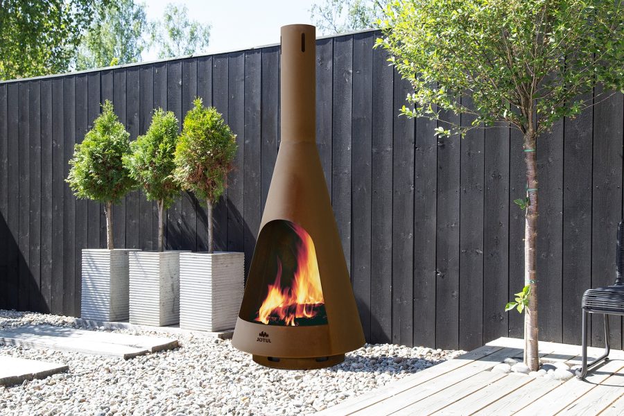 Outdoor fireplace next to a fence with some trees