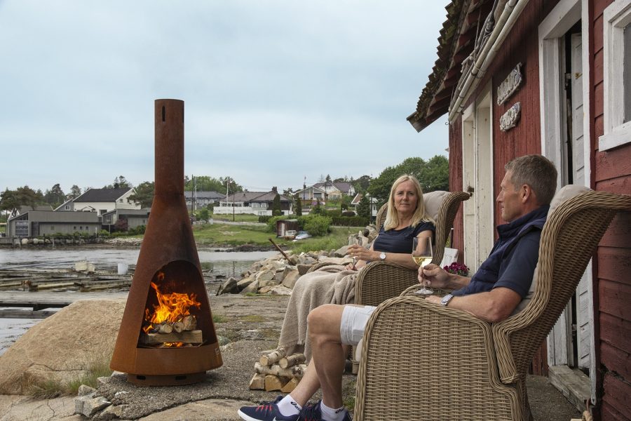 Lifestyle photo of an outdoor fireplace next to the ocean with some people sitting next to it