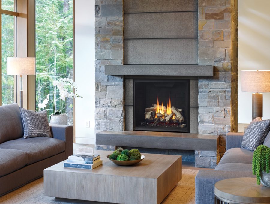 Fireplace insert with a stone frame in a room with a large window and grey comfortable furniture