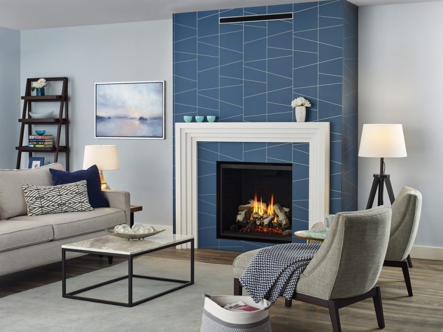 Fireplace insert with blue tiles behind it and a white frame in a well decorated room with comfortable furniture