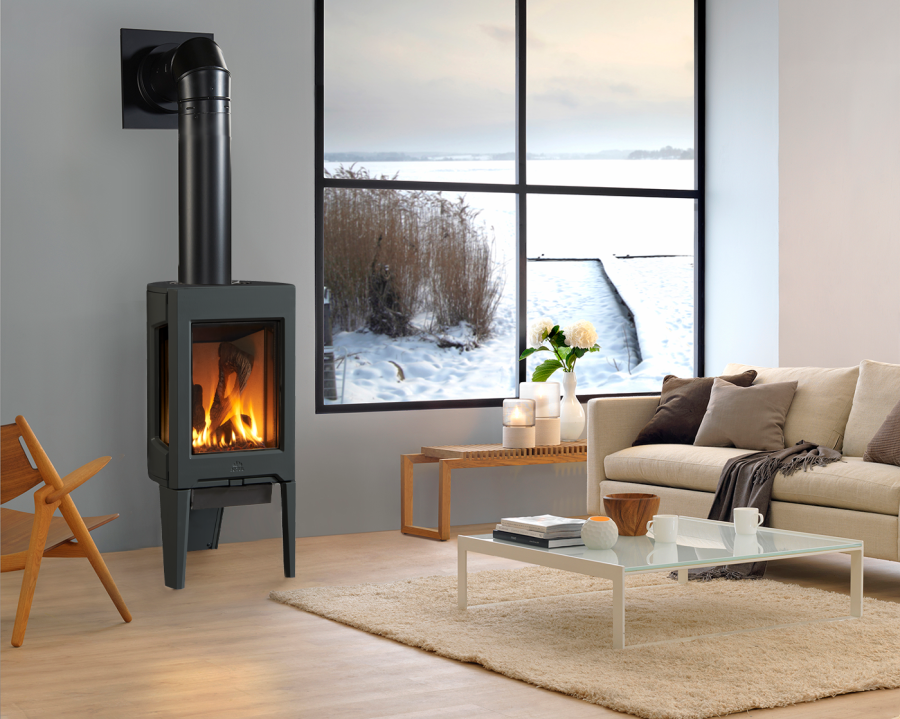 Black gas stove next to a windows showing a snowy landscape