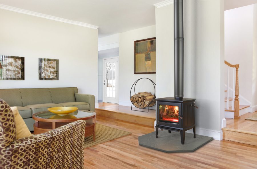 Small black wood stove in a cozy room with wood floors and painting on the walls