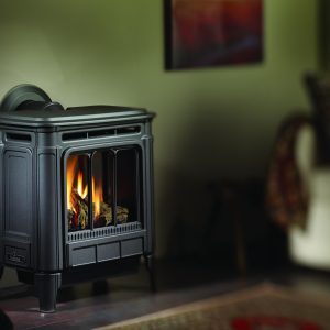 Black gas stove against a green wall with some elegant furniture and a painting on the wall