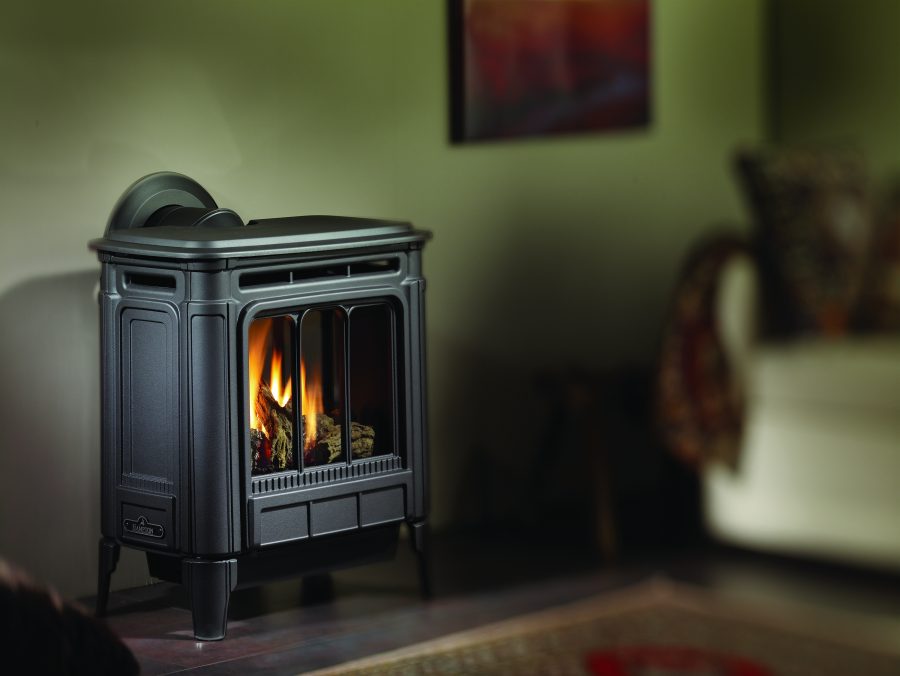 Black gas stove against a green wall with some elegant furniture and a painting on the wall