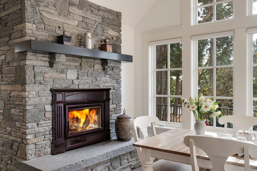 Wood fireplace insert with a stone chimney with windows in the background