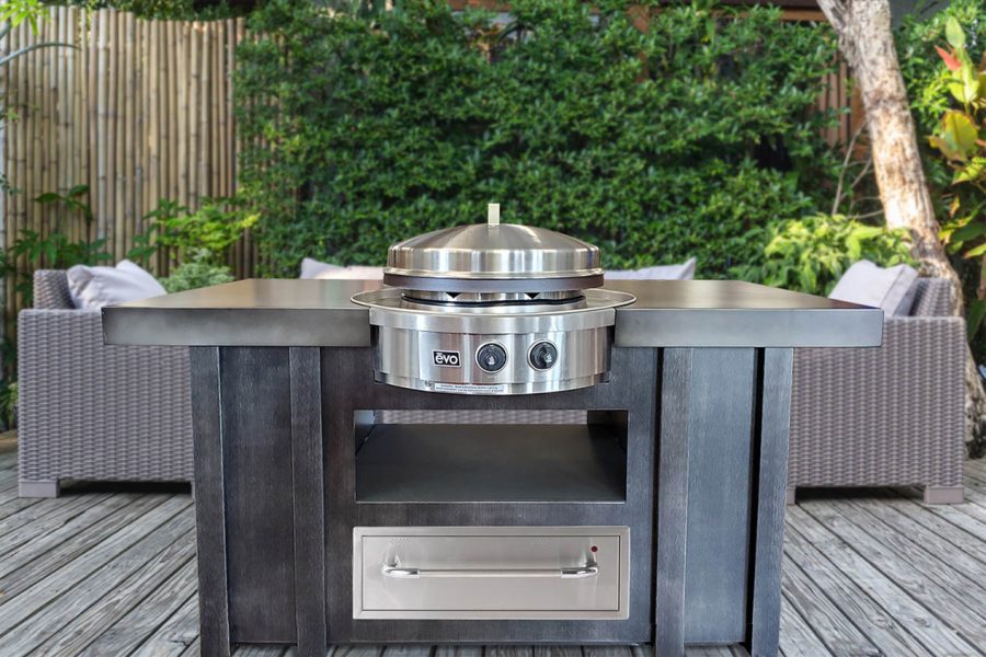 Outdoor kitchen grill with woods in the background and a sitting area