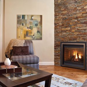 Small gas fireplace insert in a sitting room with a office in the background and a brick surround