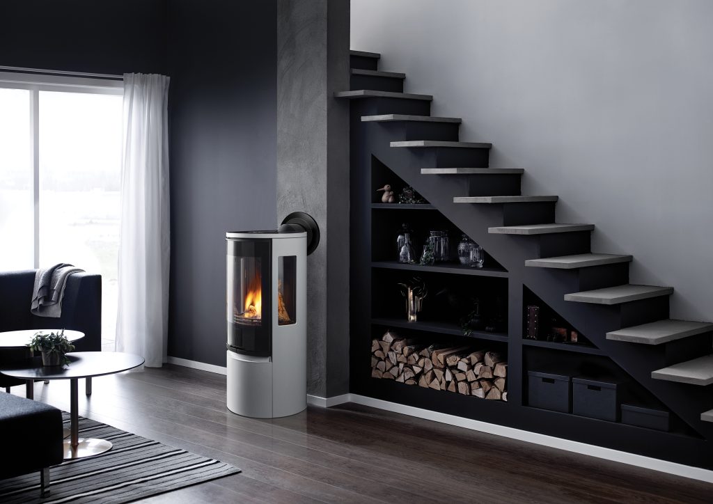 Grey stove in a modern grey home with a staircase, bookshelf, and a glass door in the background