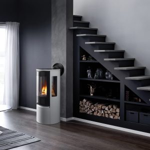 Grey stove in a modern grey home with a staircase, bookshelf, and a glass door in the background