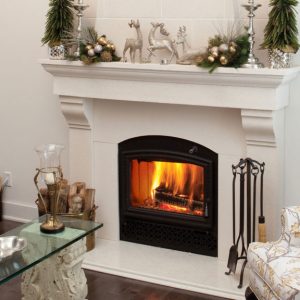 Fireplace insert with a white surround and a fire going with some flowers sitting on the mantel