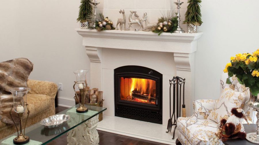 Fireplace insert with a white surround and a fire going with some flowers sitting on the mantel