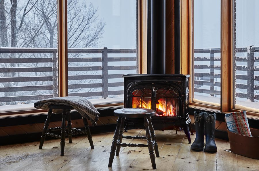 Gas fireplace in a small room with large windows showing a snowy balcony