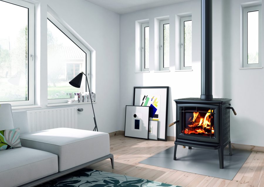 Small black woodstove in a white room with four small windows and some paintings as well as a large window