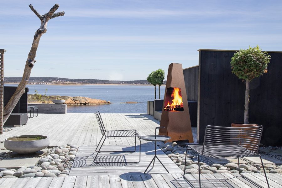 Outdoor wood fireplace on a patio next to the ocean with some seats