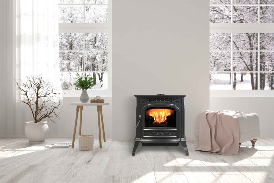 Pellet stove in a white room with windows behind it showing a snowy landscapte