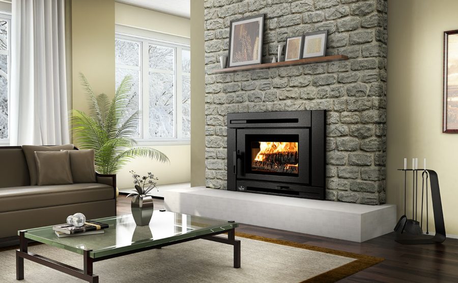 Wood fireplace insert in a living room with a plant, table, windows and sliding glass door