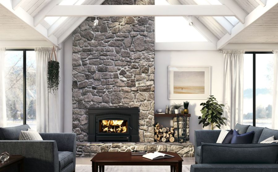 Wood fireplace insert with a stone surround and chimney in a modern living room with open white rafters and large windows