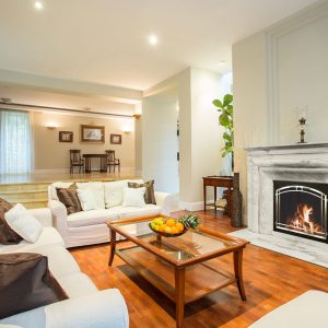 Living room with a fireplace, white couches, wood floors and a table