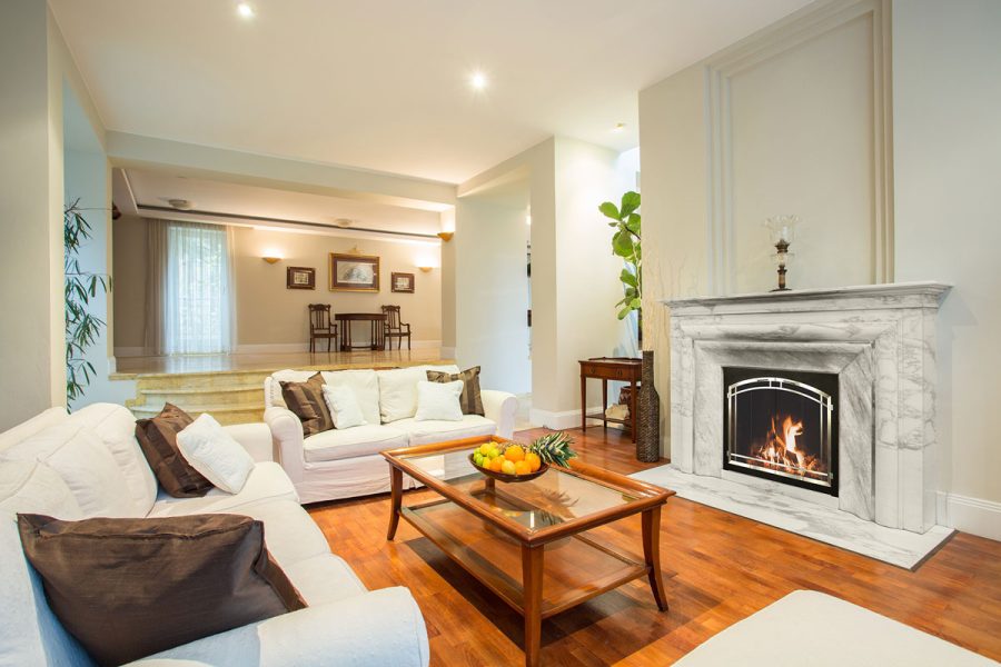 Living room with a fireplace, white couches, wood floors and a table