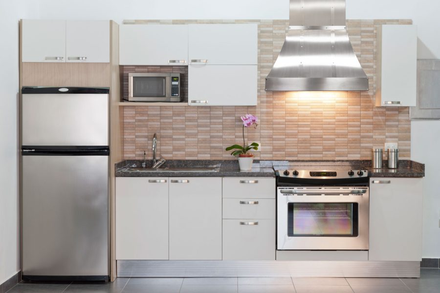 Small white kitchen with a stainless steel range hood